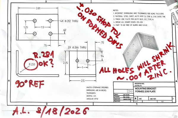 A fabrication drawing printed and marked up by hand in red after review on the shop floor.